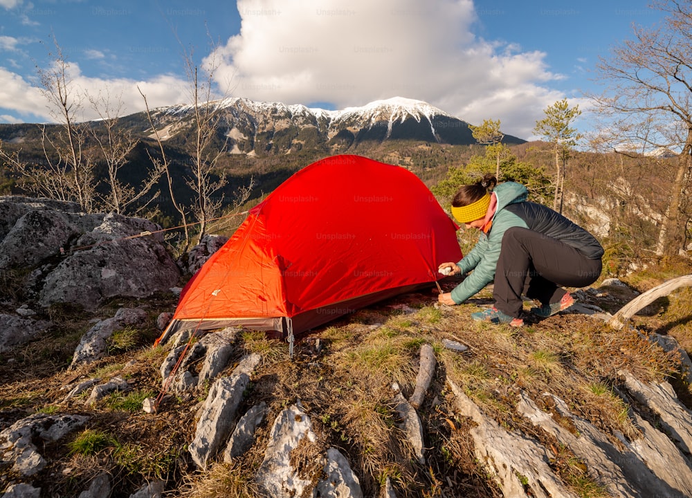 a woman setting up a tent on top of a mountain