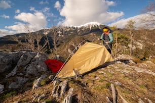 a man standing next to a tent on top of a mountain