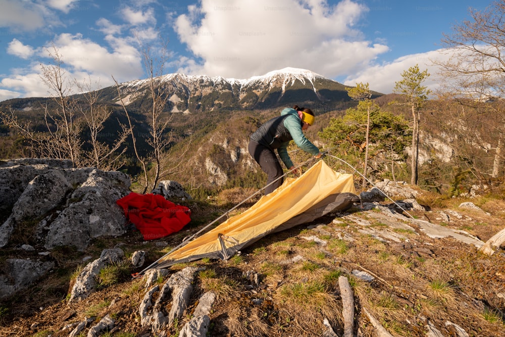 a man setting up a tent on top of a mountain