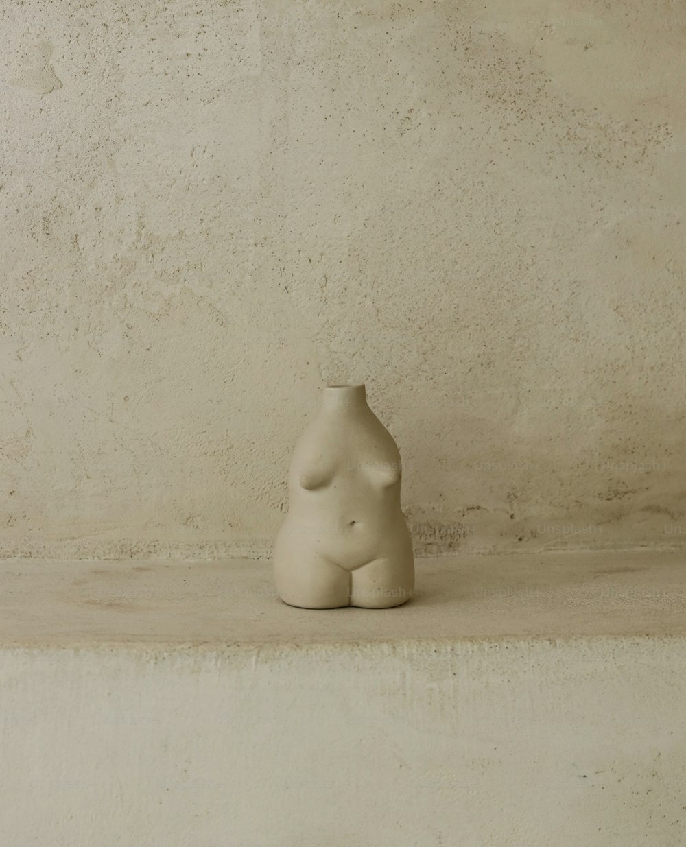 uma escultura branca sentada em cima de um degrau de cimento