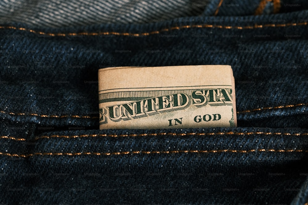 a one dollar bill sticking out of the back pocket of a pair of jeans