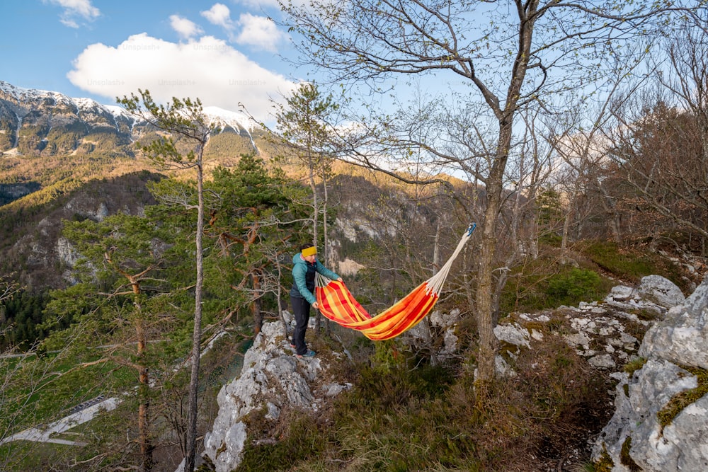a man standing on top of a mountain next to a hammock