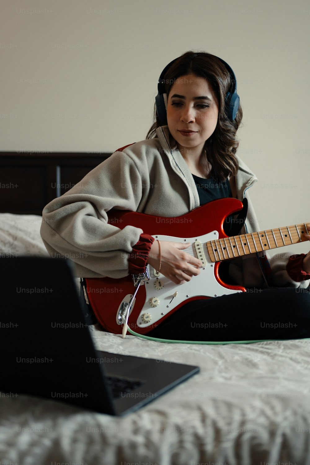 uma mulher sentada em uma cama tocando uma guitarra