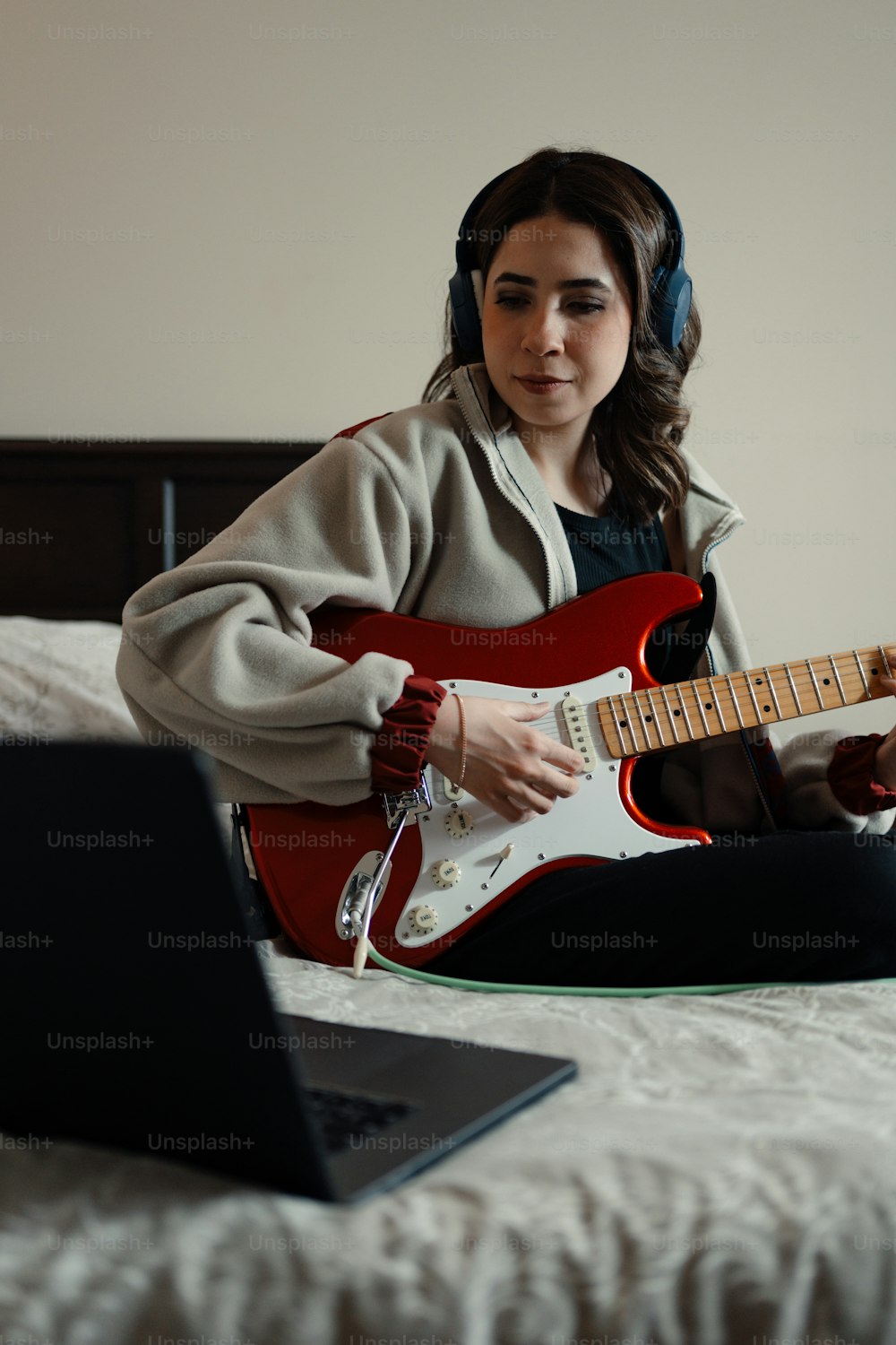 a woman sitting on a bed playing a guitar