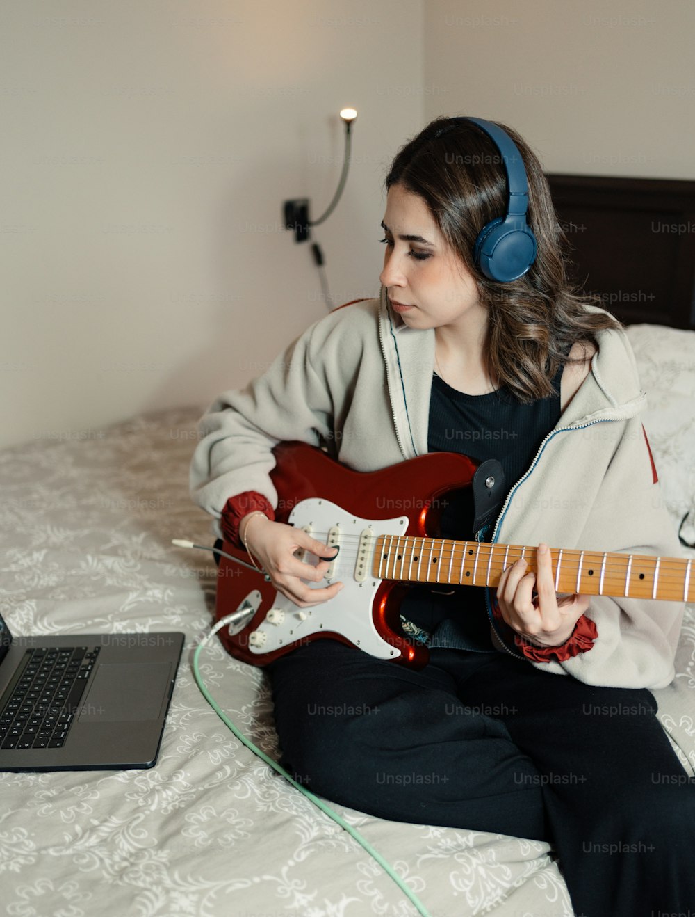 a woman sitting on a bed playing a guitar