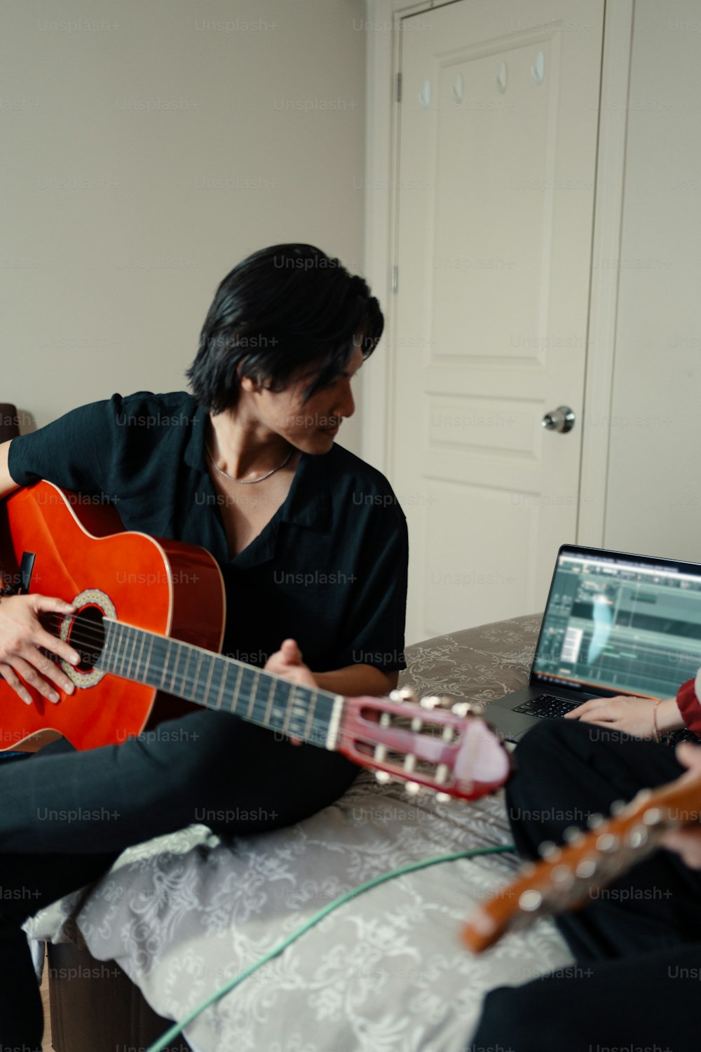 ベッドに座ってギターを弾く女性