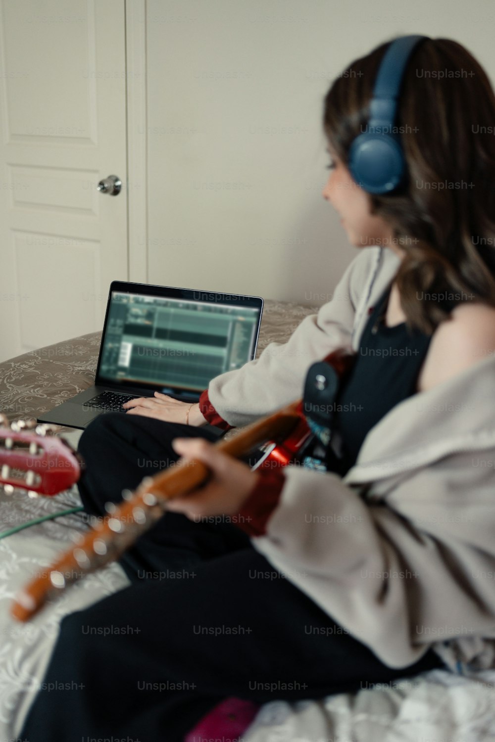 침대에 앉아 기타를 연주하는 여자