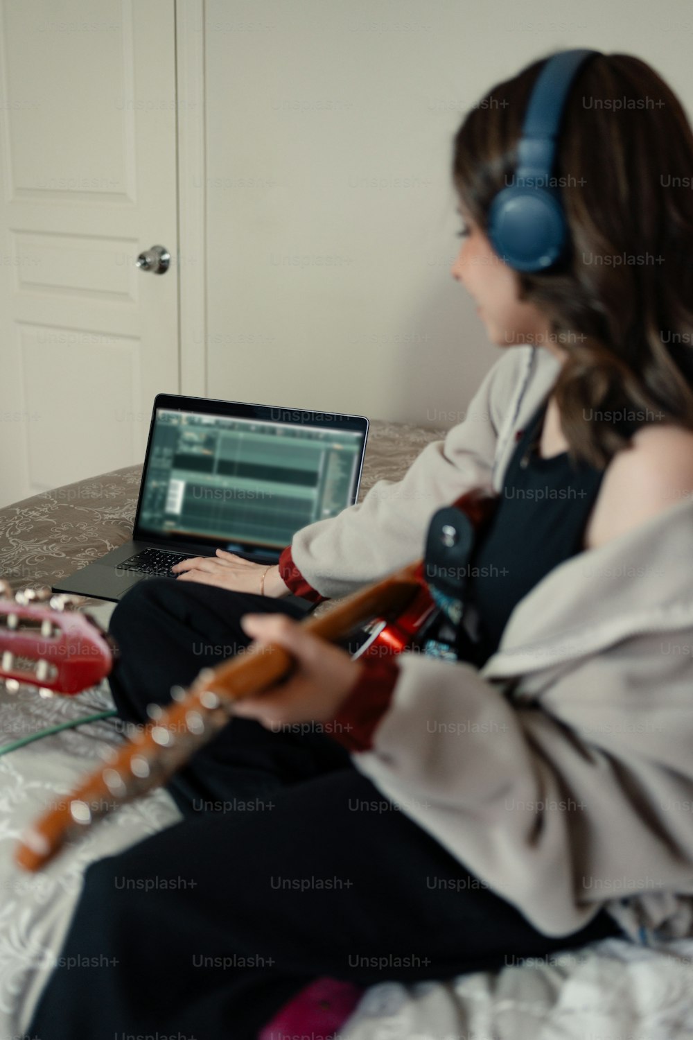 a woman sitting on a bed playing a guitar