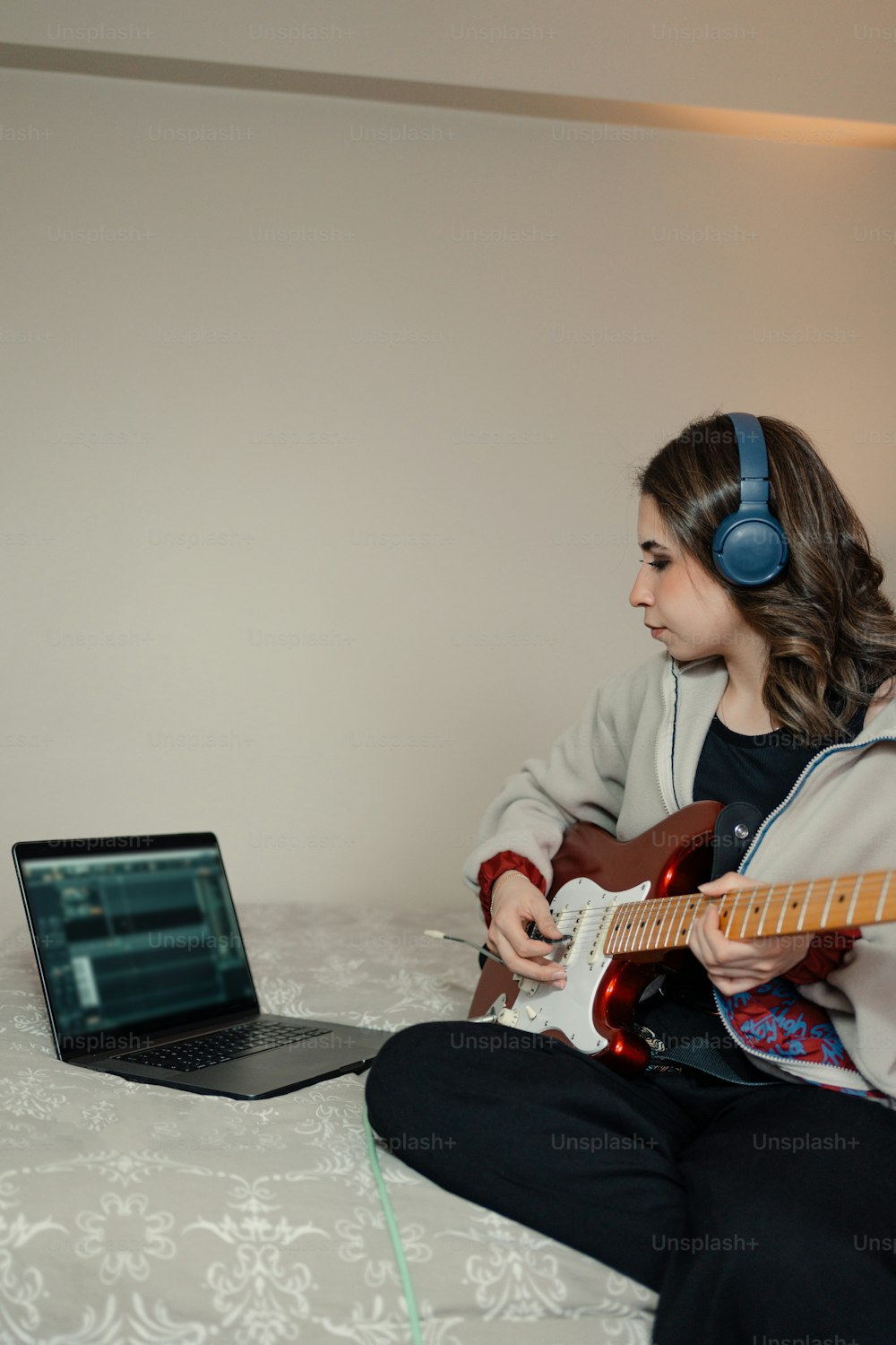 a girl sitting on a bed playing a guitar