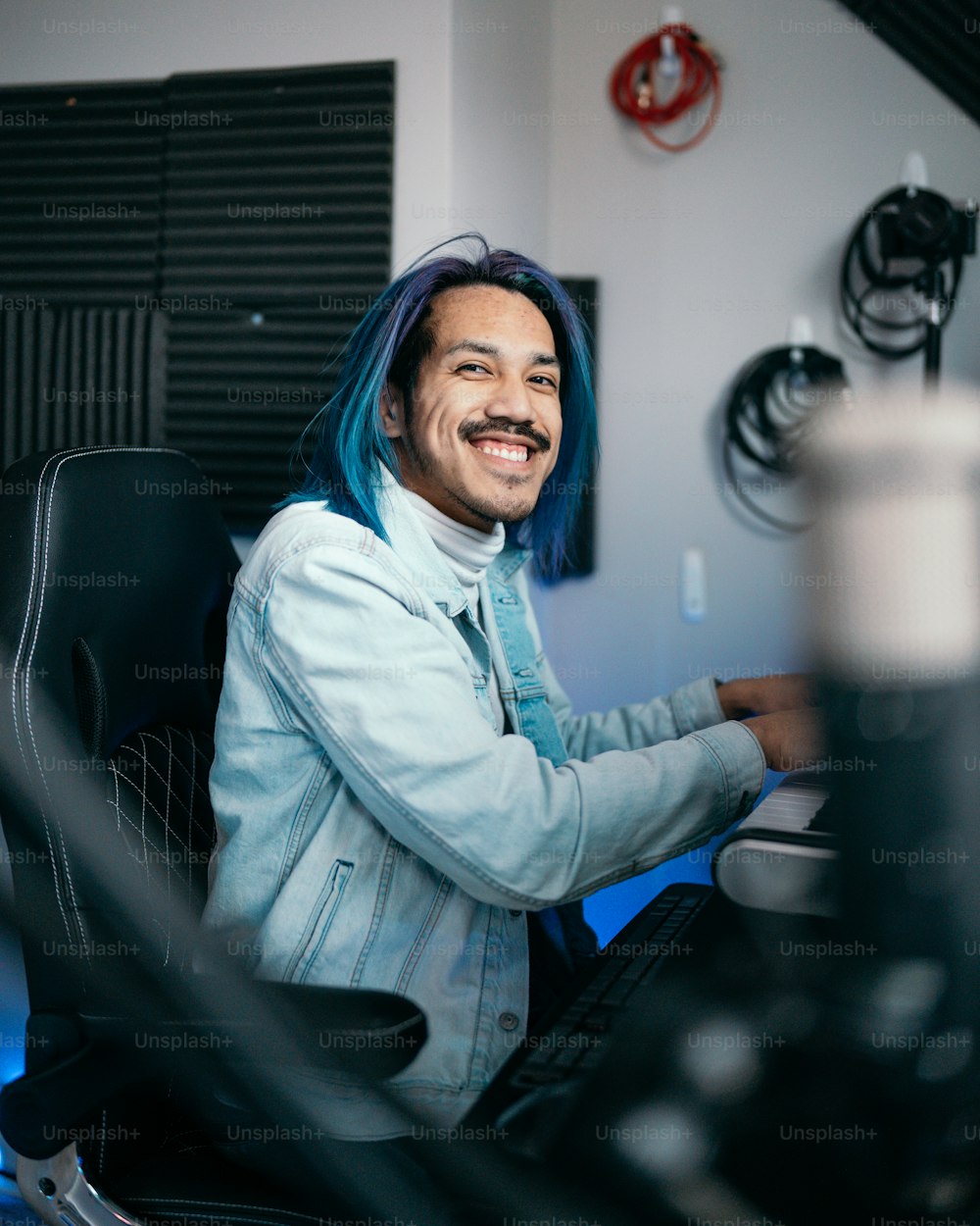 a man with blue hair sitting at a computer