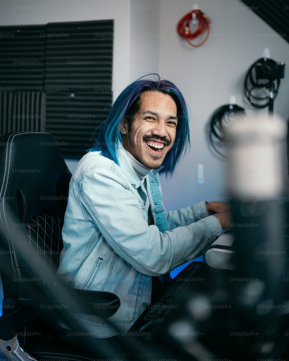 um homem com cabelo azul sentado na frente de um computador