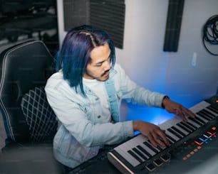 a man with blue hair playing a keyboard