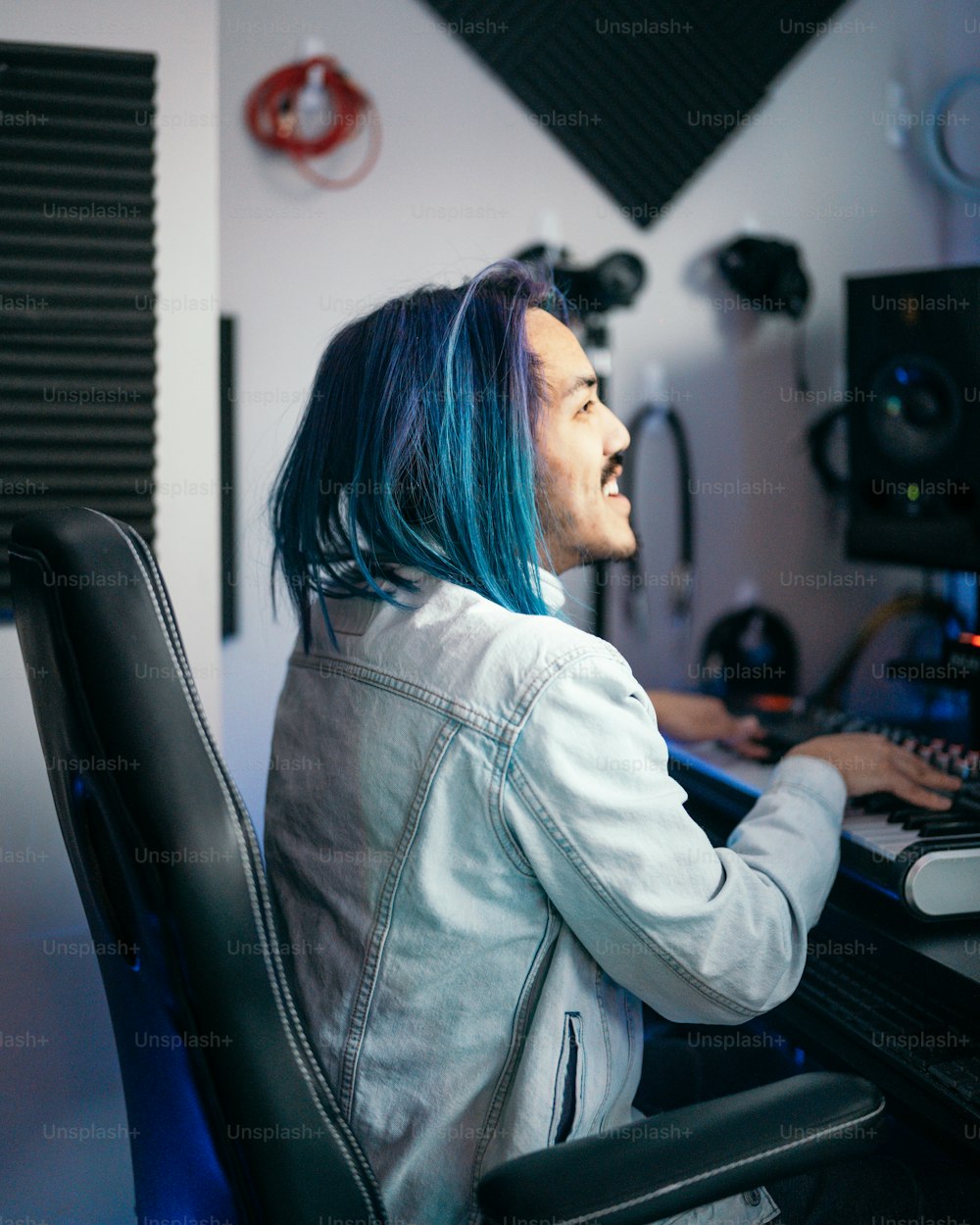 a woman with blue hair sitting in front of a computer