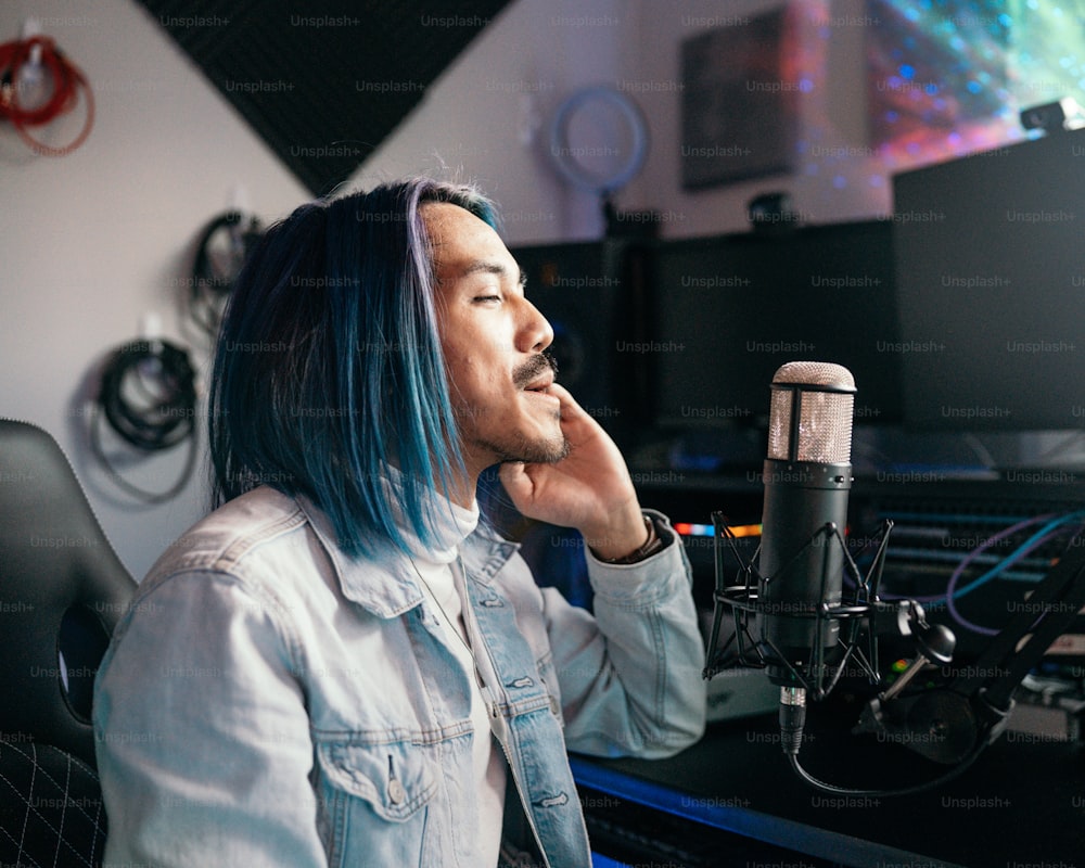 um homem com cabelo azul sentado na frente de um microfone