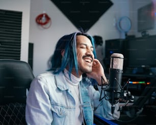 a man with blue hair is sitting in front of a microphone