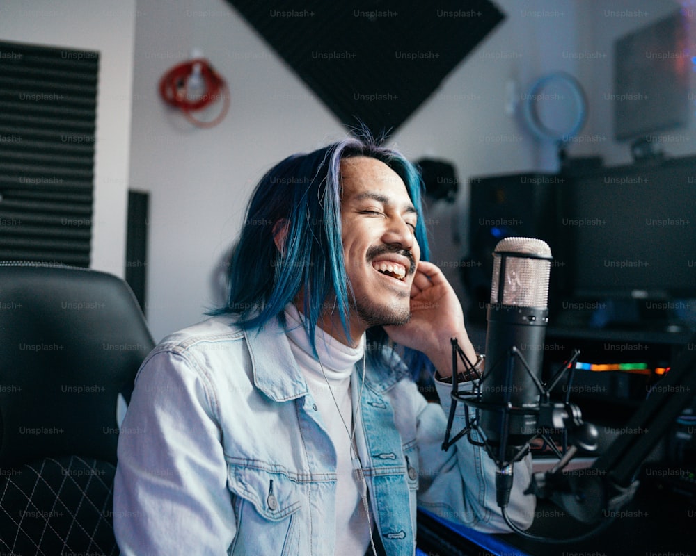 a man with blue hair is sitting in front of a microphone
