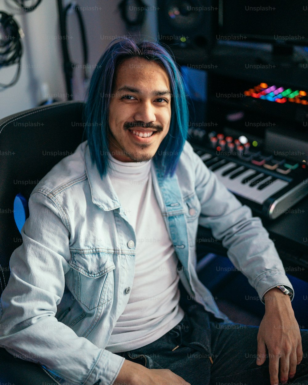 a man with blue hair sitting in front of a keyboard