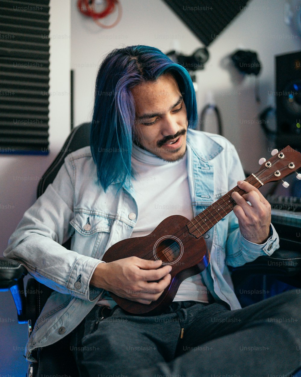 Ein Mann mit blauen Haaren spielt eine Ukulele