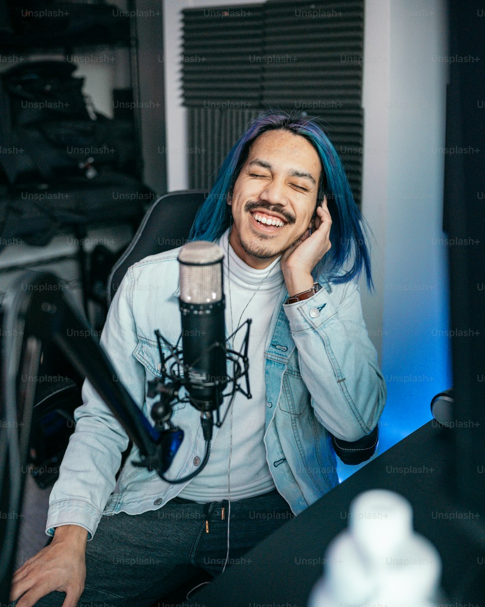 Un uomo con i capelli blu seduto davanti a un microfono