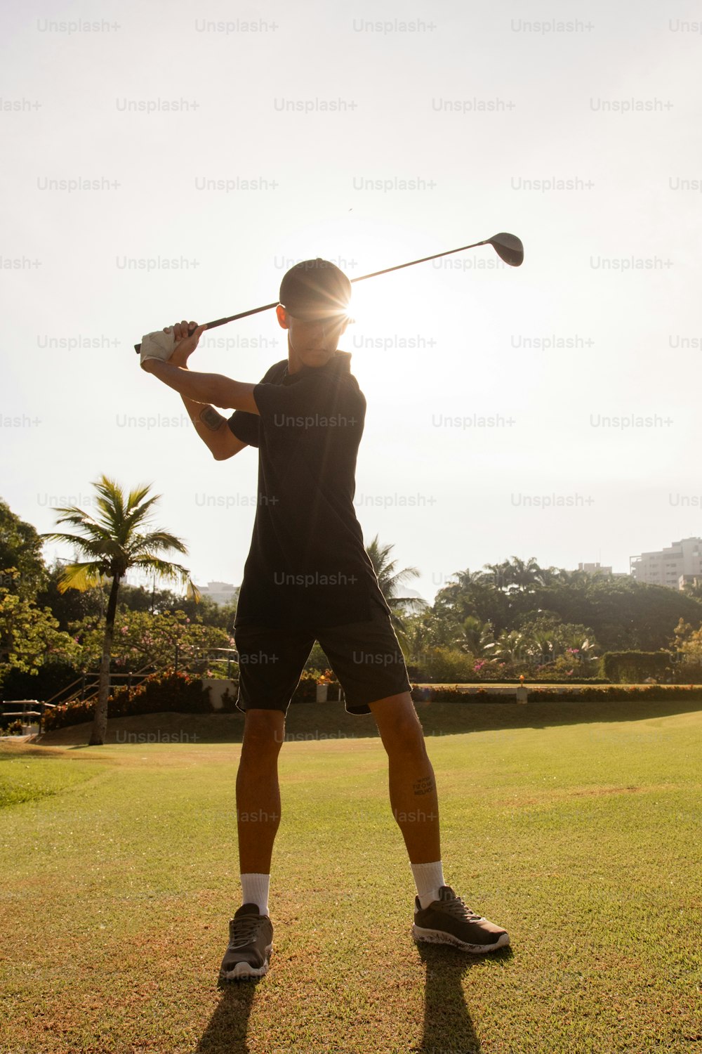 a man holding a golf club on top of a lush green field
