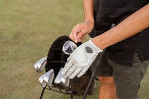 a man holding a golf club and putting it in a bag