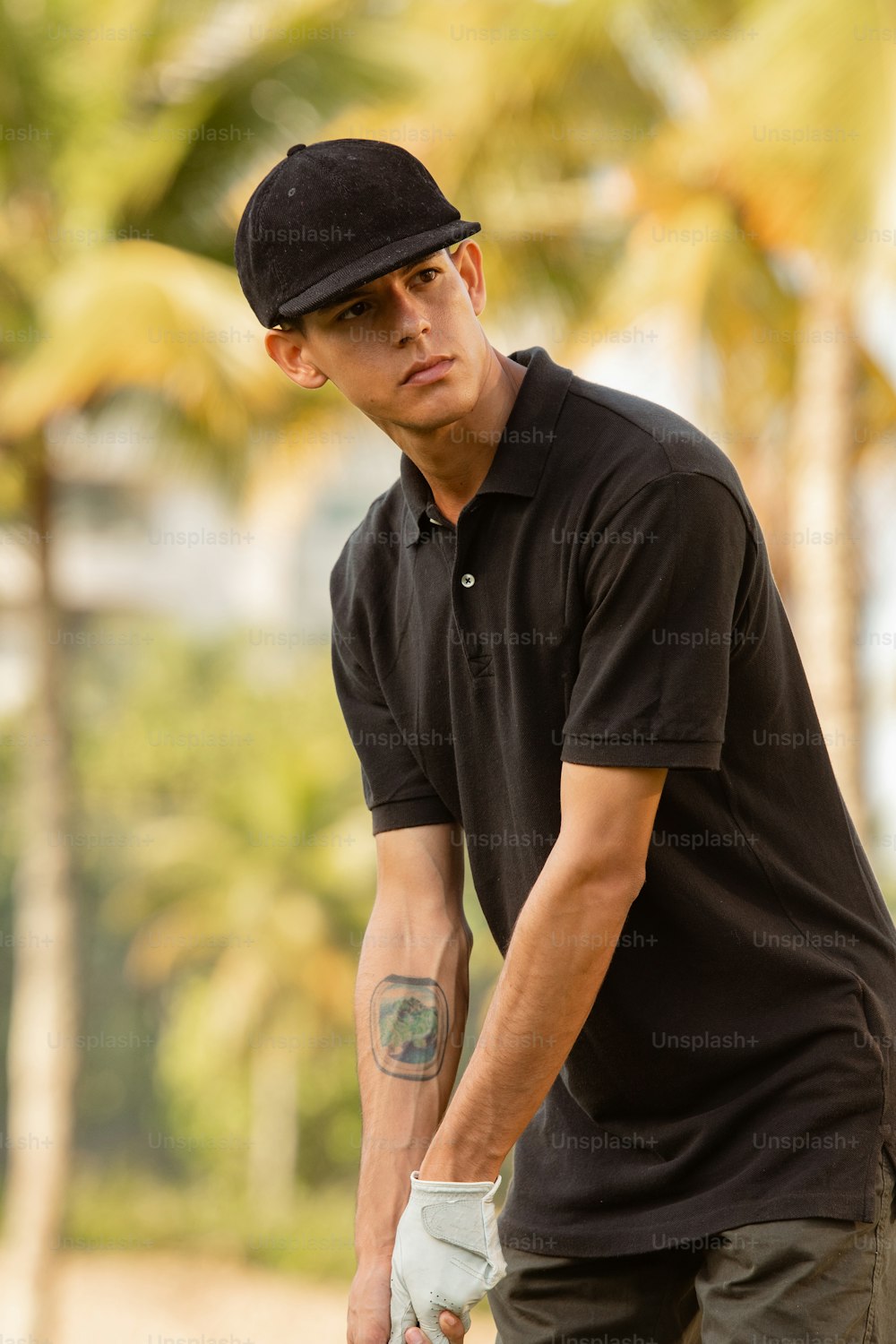 Ein Mann in schwarzem Hemd und Hut, der ein Skateboard hält