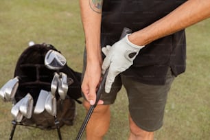 a man holding a golf club and a bag of golf clubs