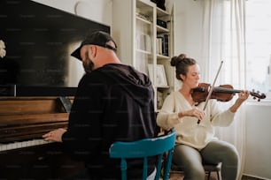 a man and a woman playing violin in front of a piano
