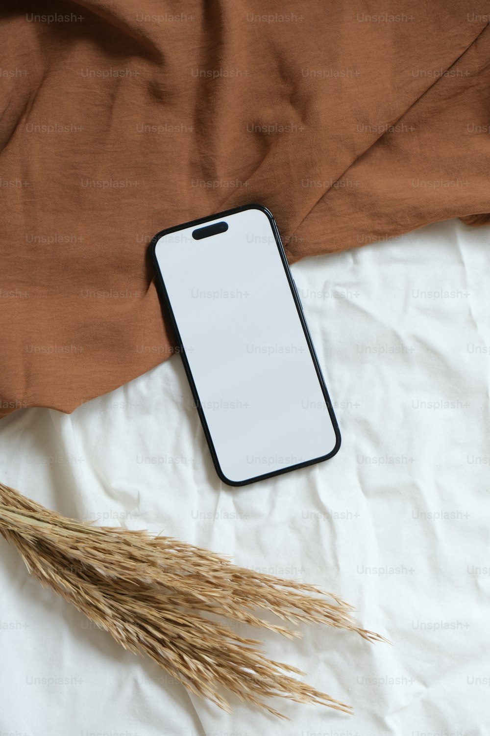 a cell phone sitting on top of a bed next to a brown blanket