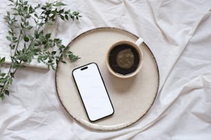 a cup of coffee and a cell phone on a plate