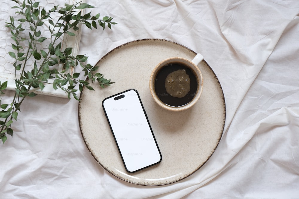 una tazza di caffè e un cellulare su un piatto