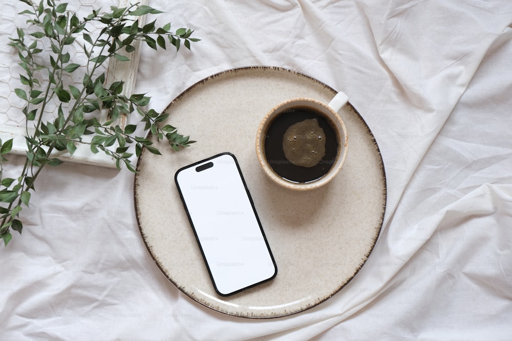 a cup of coffee and a cell phone on a plate