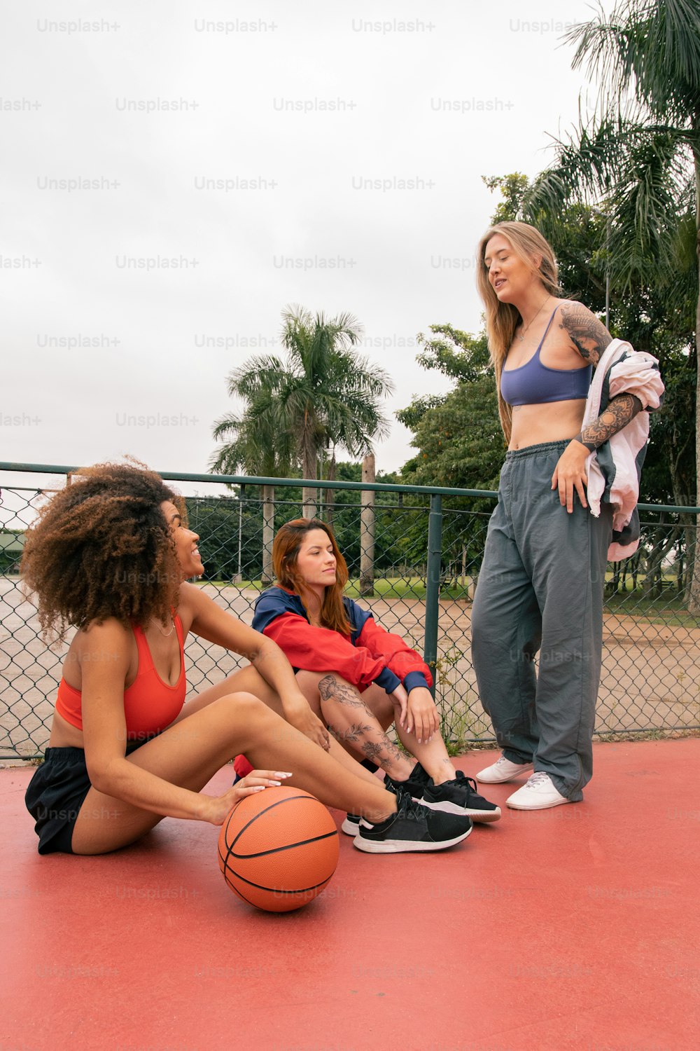 Eine Gruppe junger Frauen, die auf einem Basketballplatz sitzen