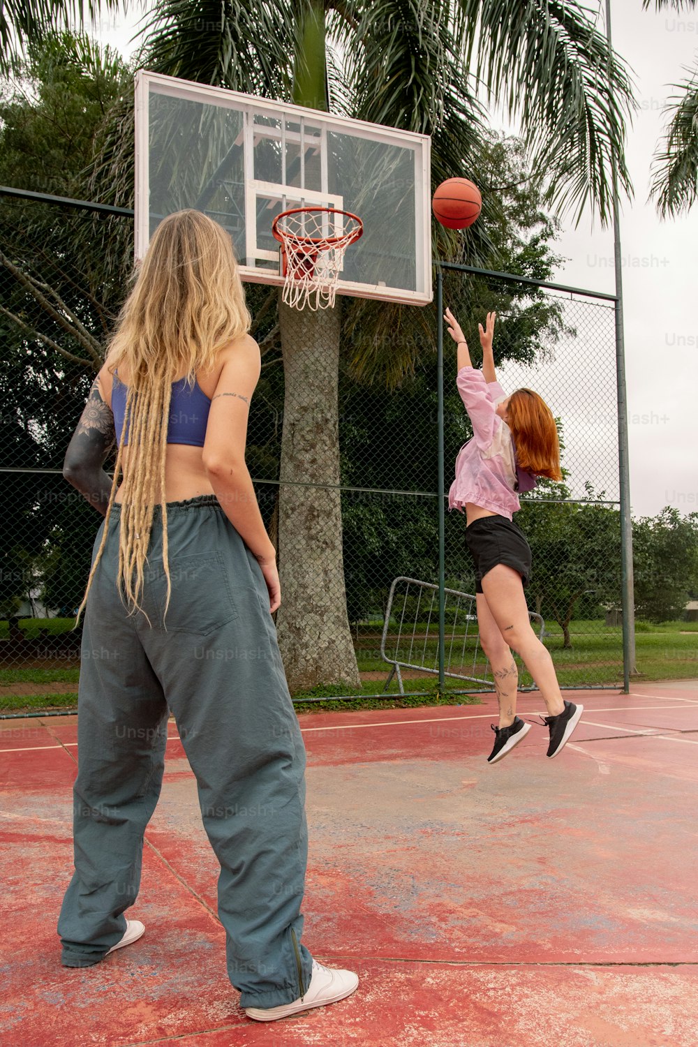 two girls playing basketball on a basketball court