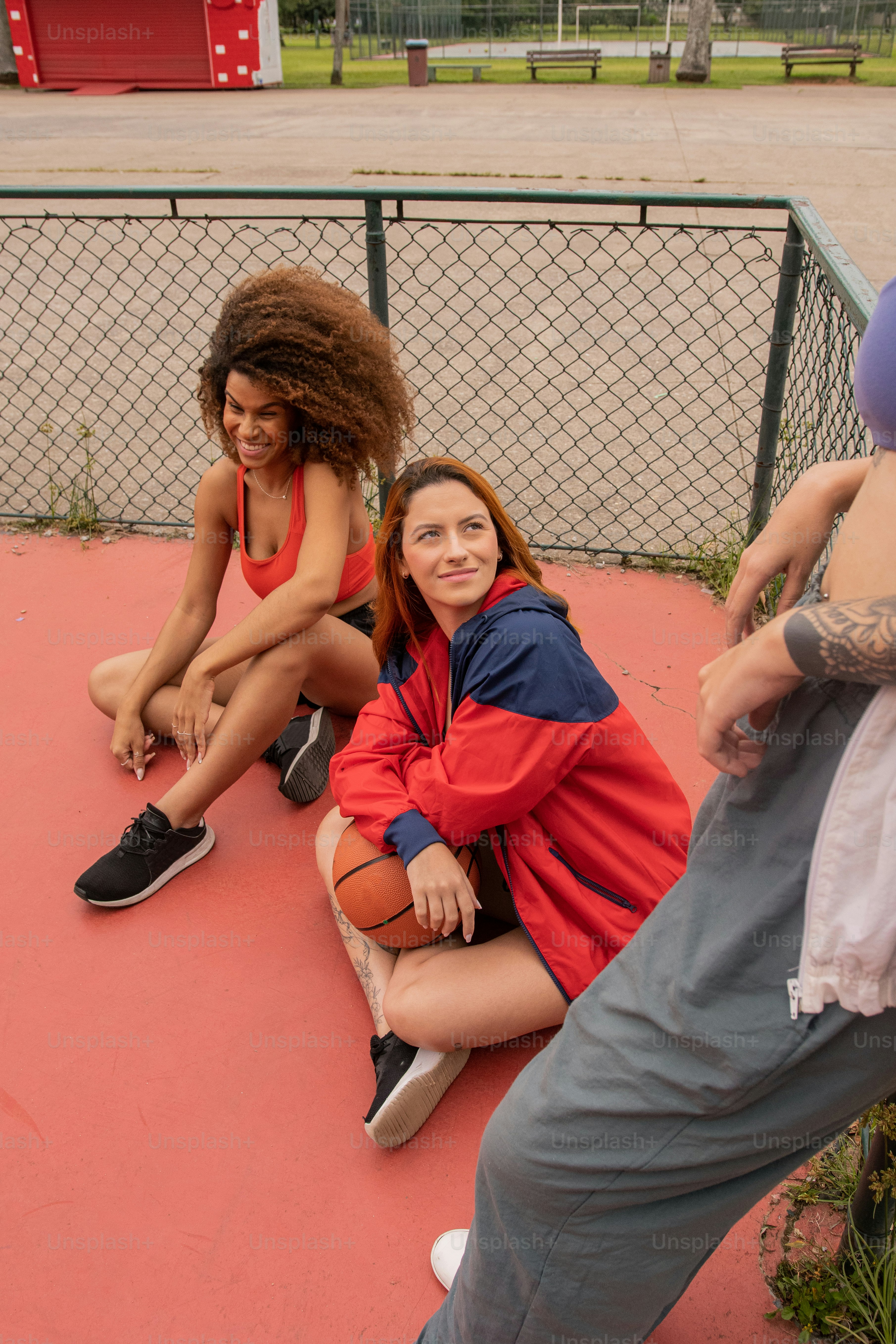 a group of people sitting on the ground next to a fence