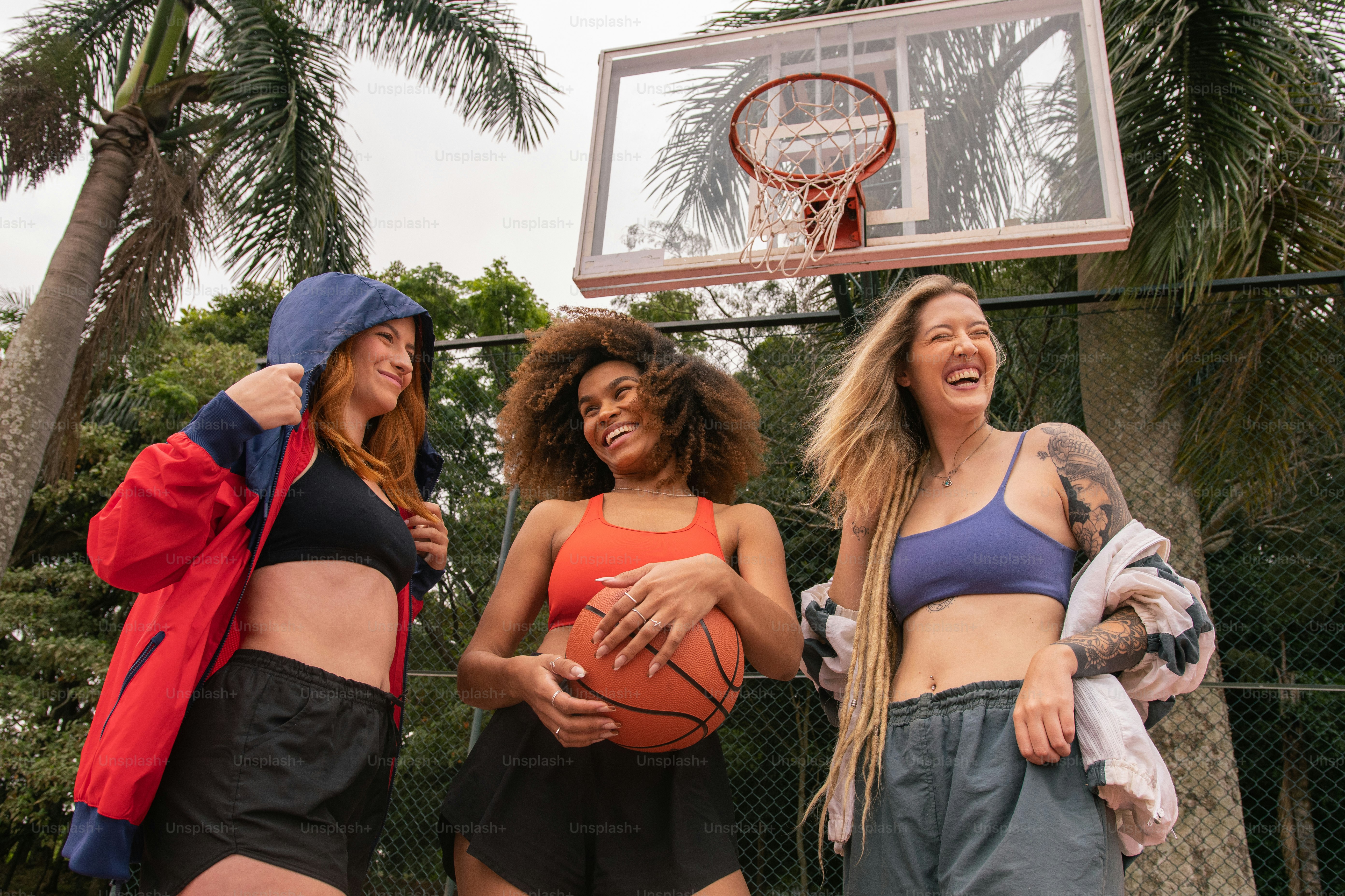 a group of women standing next to each other holding a basketball