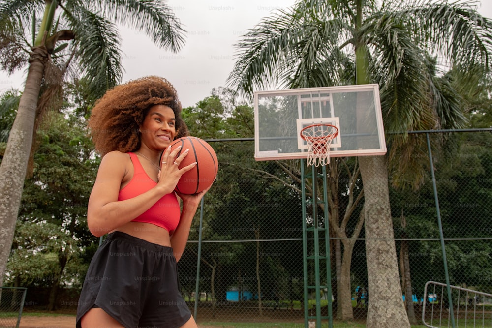 バスケットボールのフープの前でバスケットボールを持つ女性
