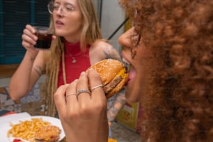a woman eating a hamburger with a glass of coke