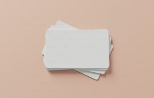 Una pila de posavasos cuadrados blancos sobre un fondo rosa