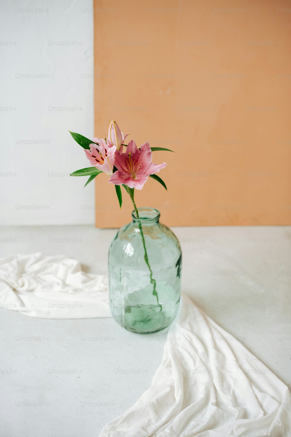eine rosa Blume in einer Glasvase auf einem Tisch