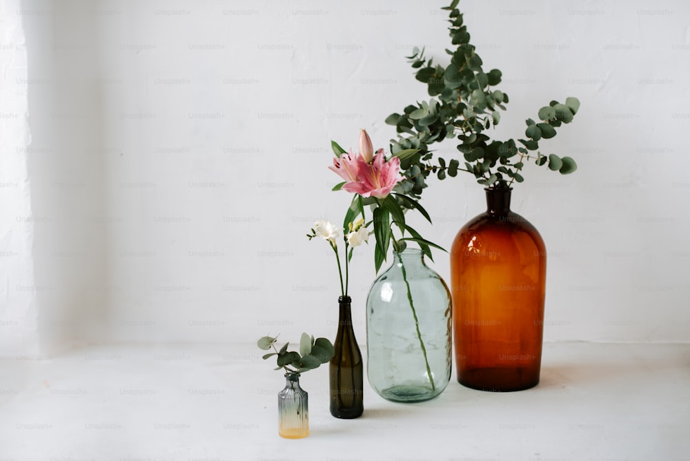 eine Gruppe von drei Vasen mit Blumen darin