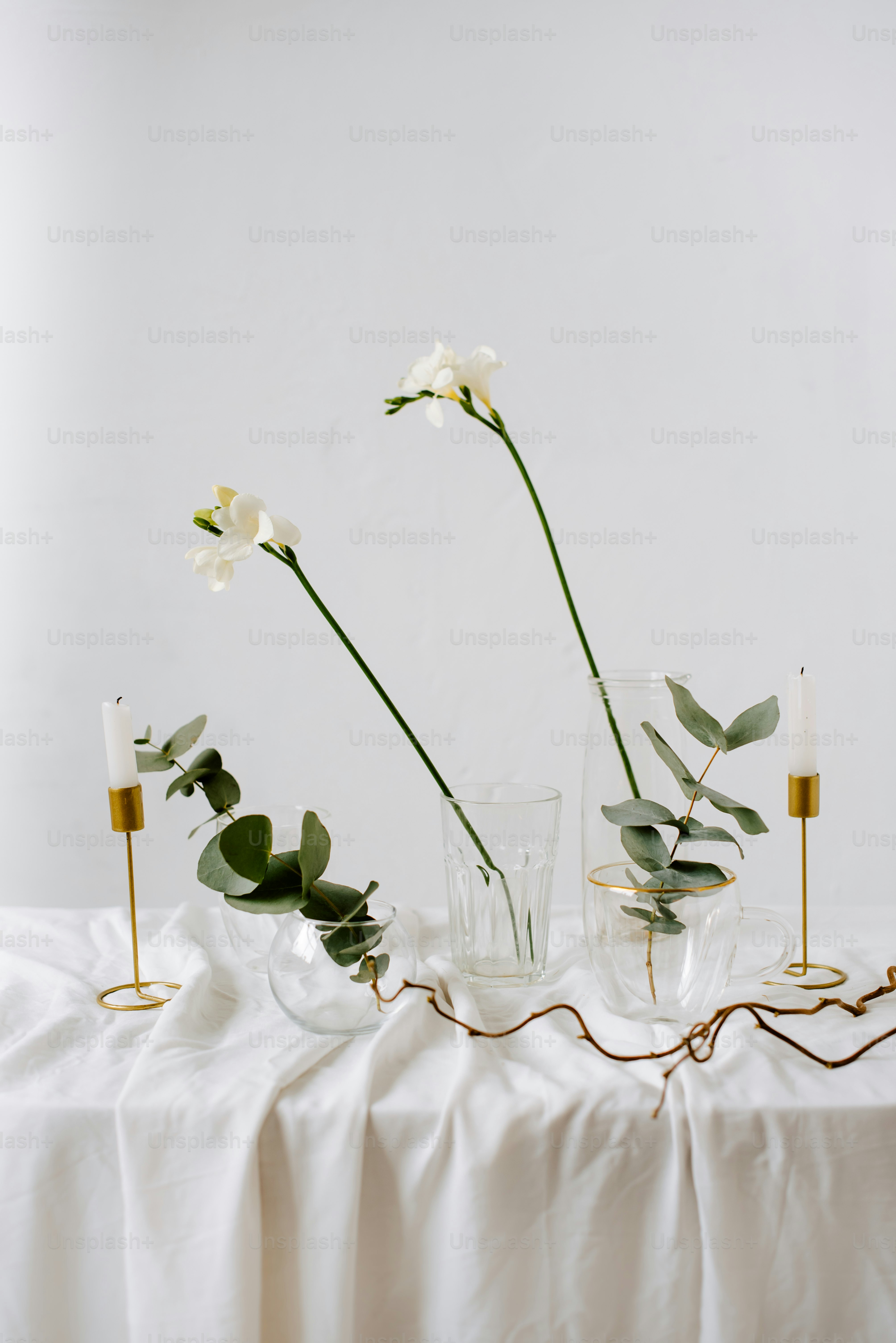 a table topped with vases filled with flowers and greenery