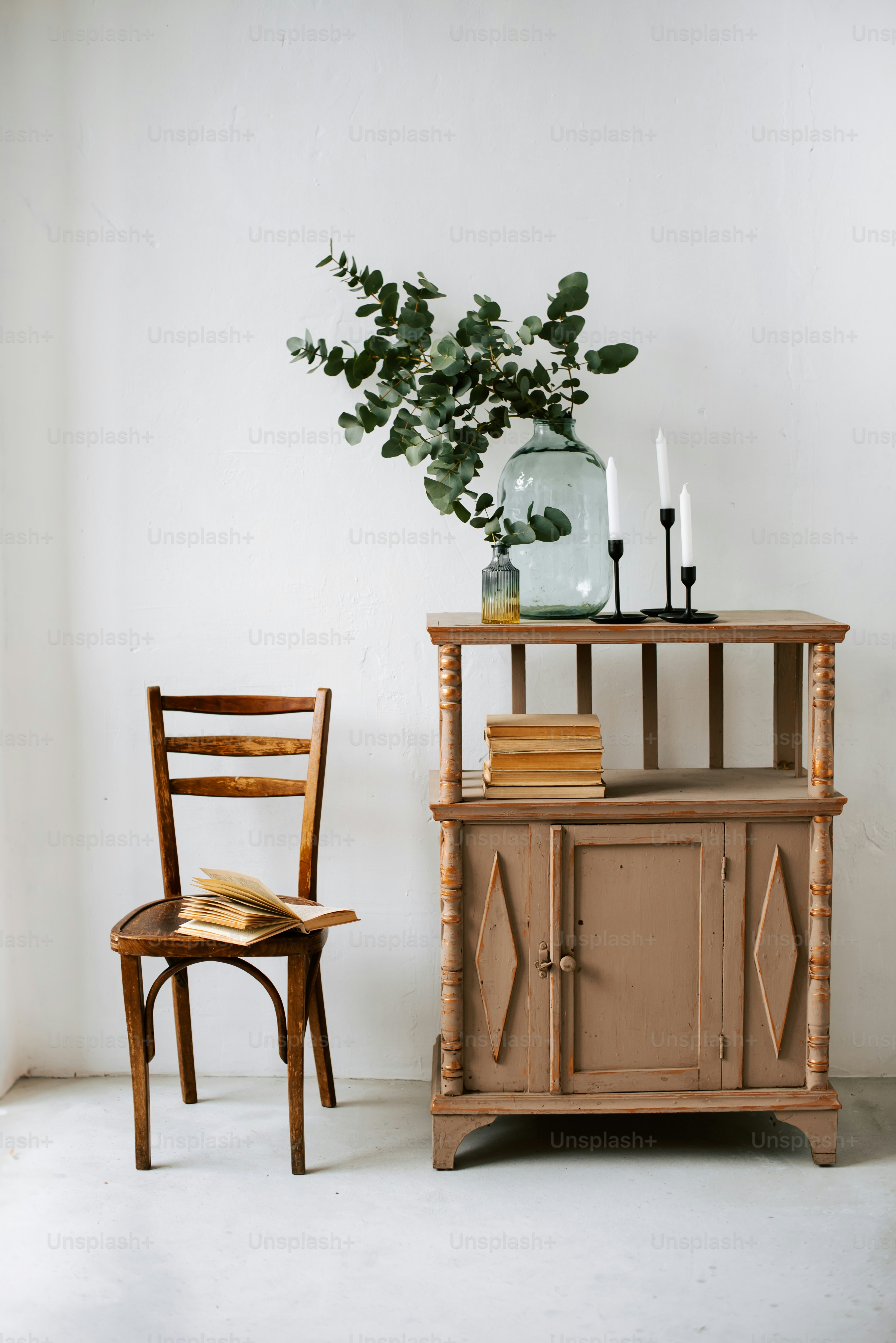 a chair next to a table with a vase on top of it