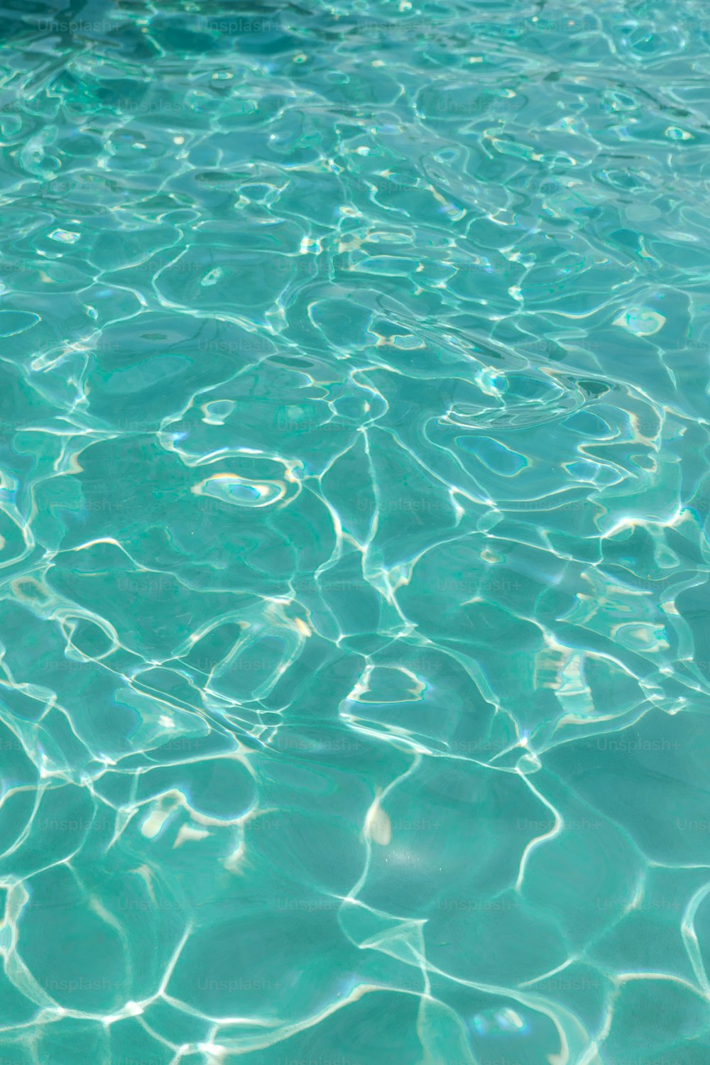 una piscina con agua azul clara y sol reflejándose en el agua