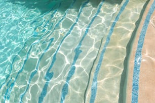 une piscine avec une eau bleue claire et le soleil se reflétant sur l’eau