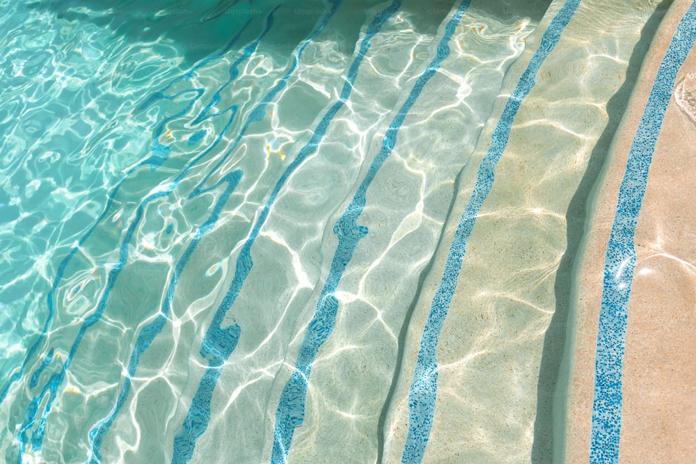 a pool with clear blue water and sun reflecting on the water