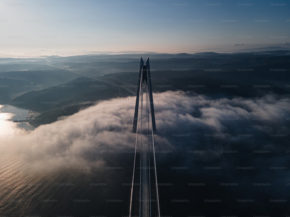 an aerial view of a bridge surrounded by clouds