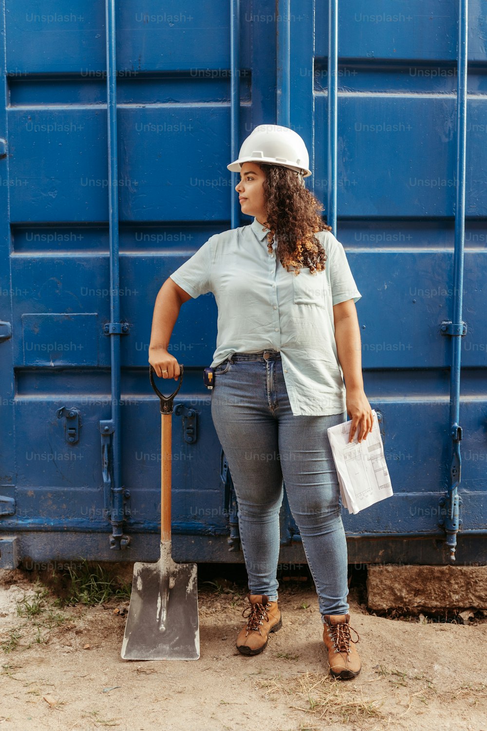 a woman standing next to a blue container holding a shovel