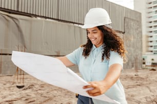 a woman in a hard hat holding a blueprint