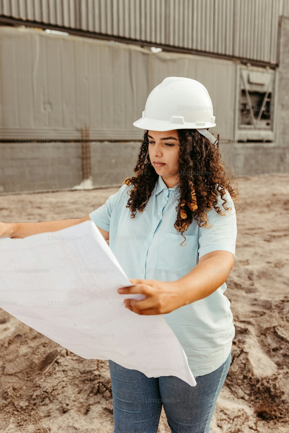 a woman in a hard hat looking at a blueprint